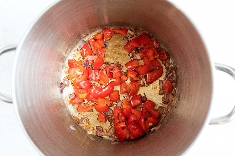 overhead view of sauting peppers and onions in pot for beef cabbage soup recipe