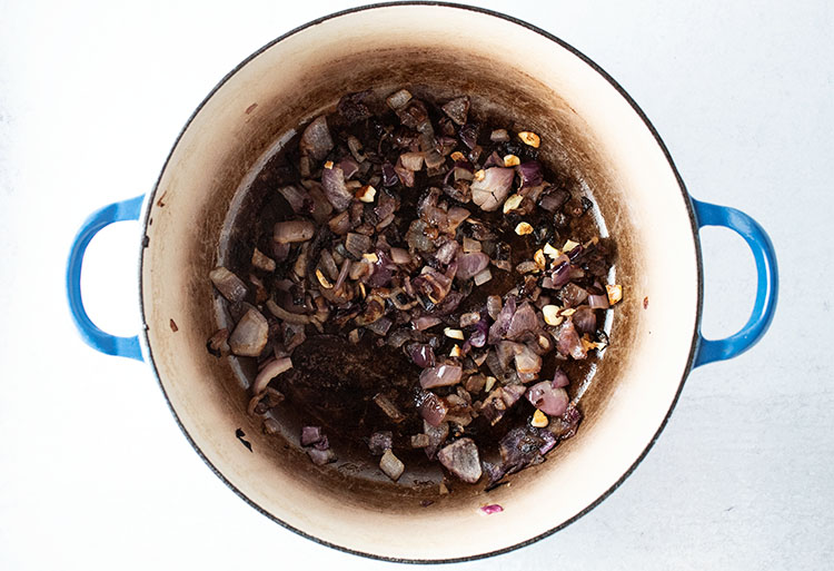 overhead view of chopped onion and olive oil in blue pot for how to make veggie soup