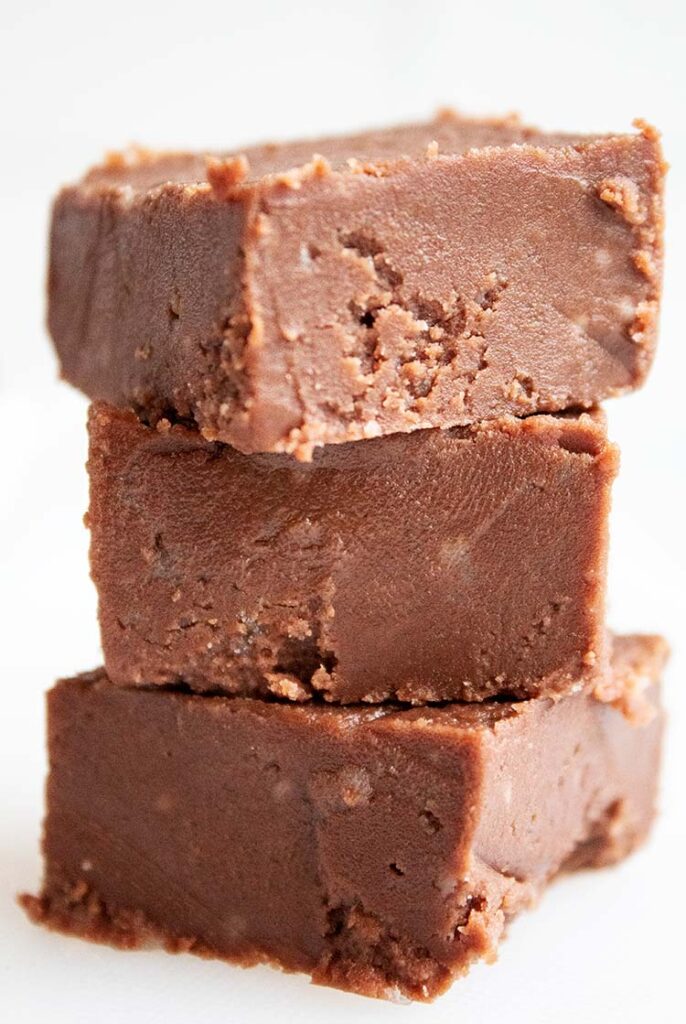 sideview of stack of three pieces of chocolate microwave fudge on white countertop