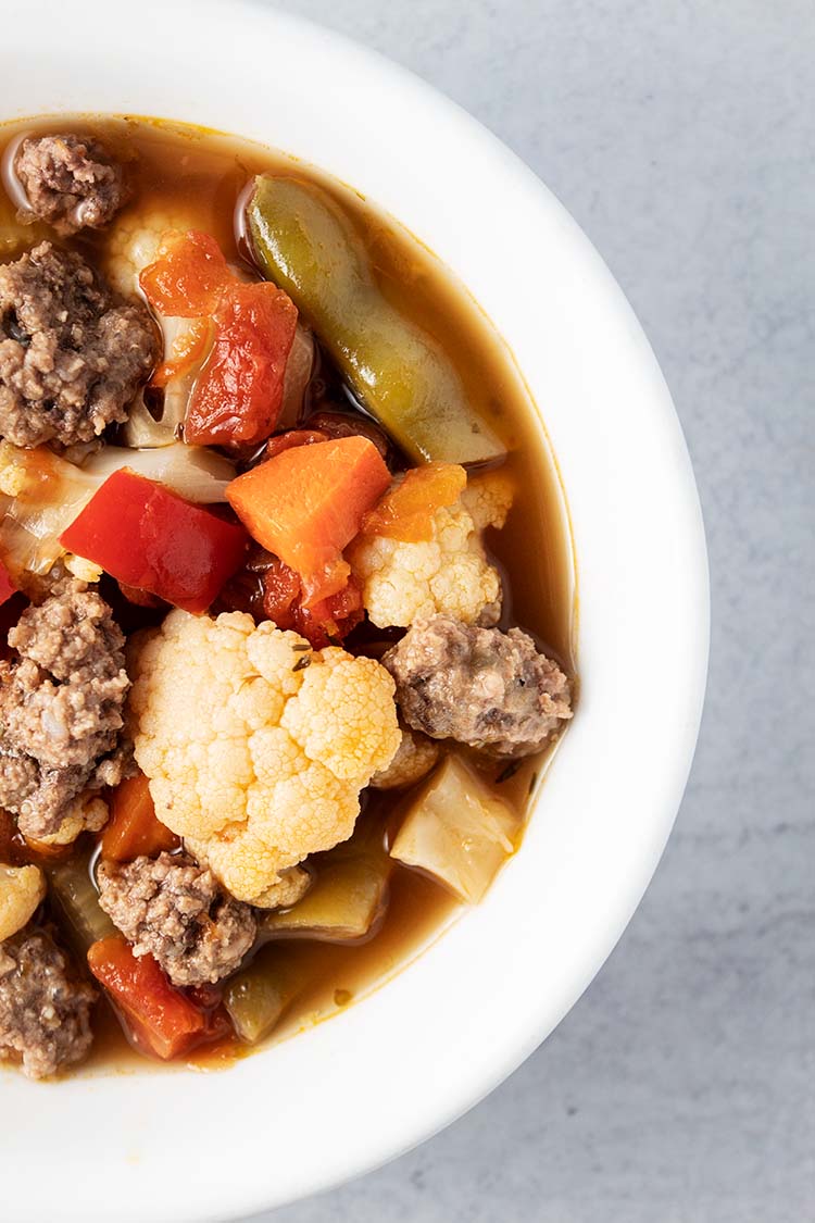 overhead view of vegetable beef soup in white bowl