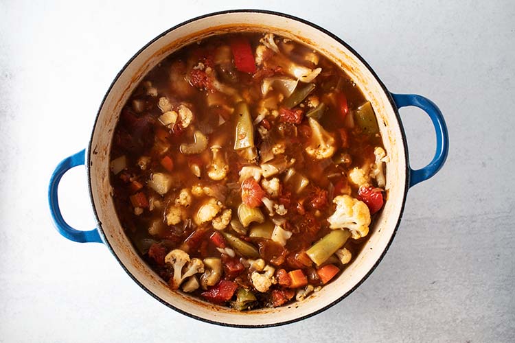 overhead view of fully cooked vegetable soup in blue pot for how to make the best homemade vegetable soup