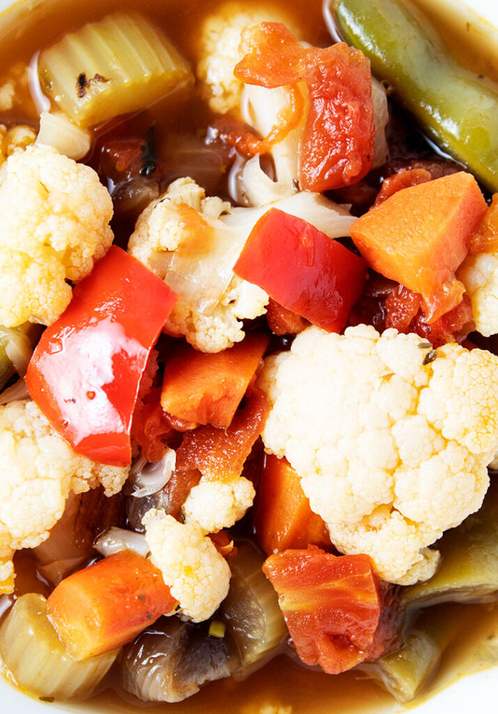 closeup view of veggie soup with carrots, green beans, red peppers and cauliflower
