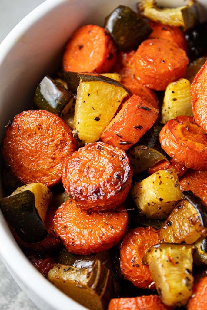 overhead view of a white serving bowl of roasted zucchini and carrots