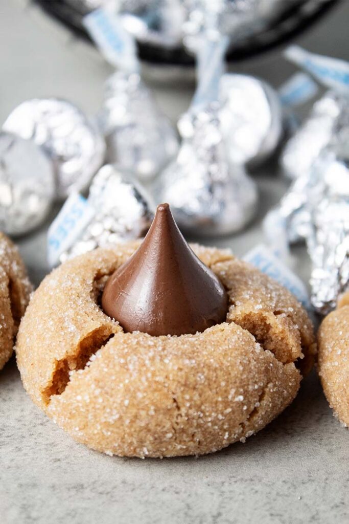 peanut butter blossom cookie with wrapped hershey's kisses behind them