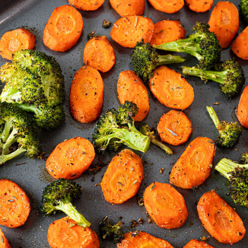 overhead view of roasted broccoli and carrots on metal sheet pan after baking