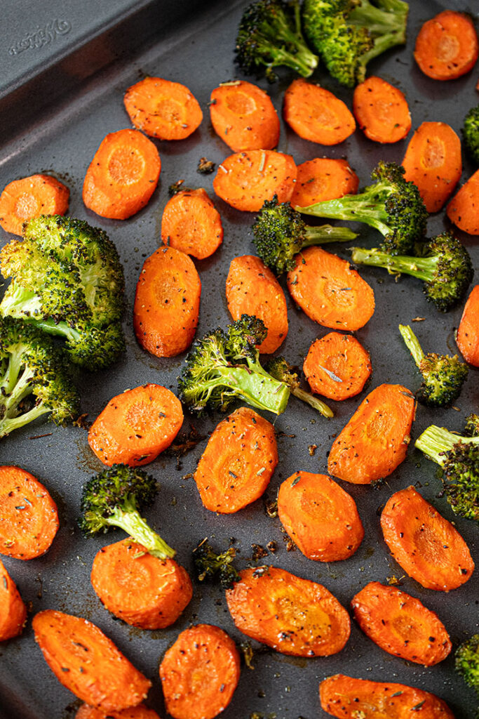 overhead view of roasted broccoli and carrots on metal sheet pan after baking