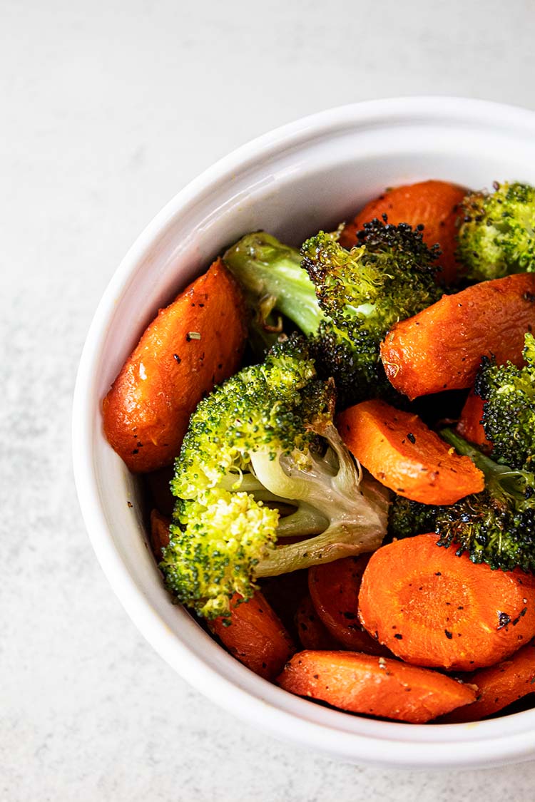 overhead view of roasted broccoli and carrots in white serving bowl