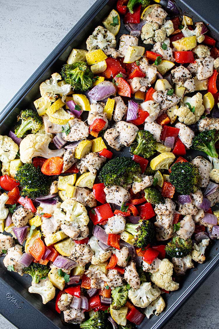 overhead view of sheet pan roast chicken and veggies including broccoli, cauliflower, red bell peppers, squash and zucchini