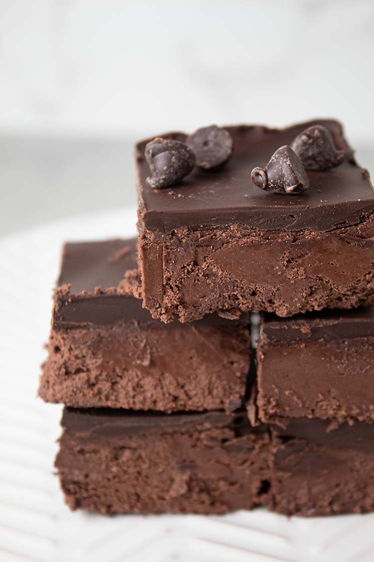 sideview of stack of easy chocolate heaven dessert bars stacked on a white serving dish