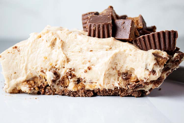sideview of piece of no bake peanut butter pie with chopped reeses cups