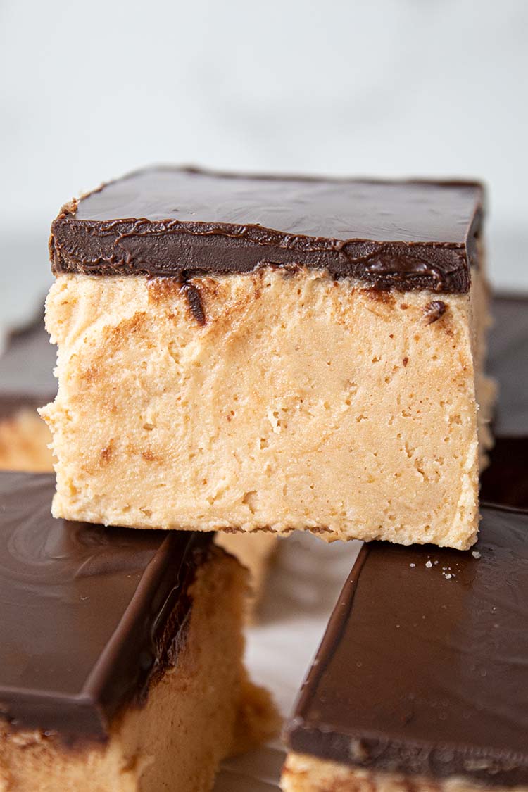 sideview of numerous peanut butter heaven dessert bars topped with chocolate ready to serve