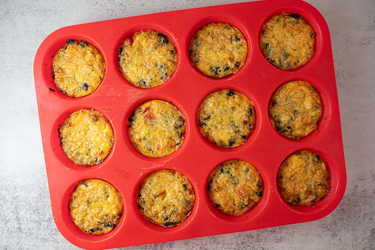 overhead view of a red silicone cupcake mold with egg breakfast muffins cooling off