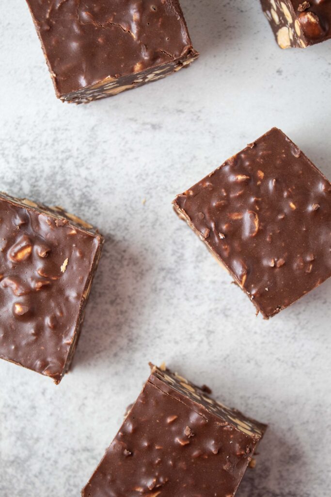 overhead view of pieces of peanut butter chocolate crunch bars spread across a white surface