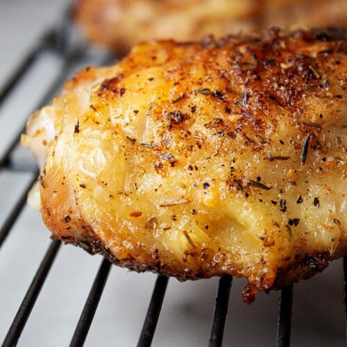 sideview of two pieces of crispy air fryer garlic parmesan chicken on a cooling rack