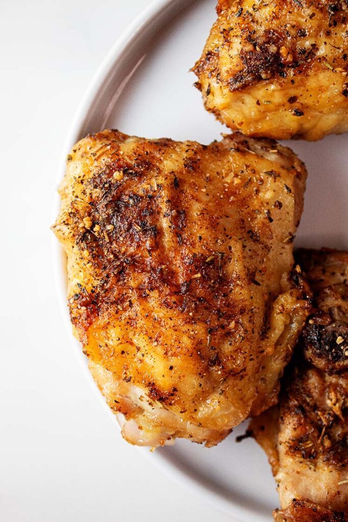 overhead view of air fryer garlic parmesan chicken thighs on a white plate ready to serve