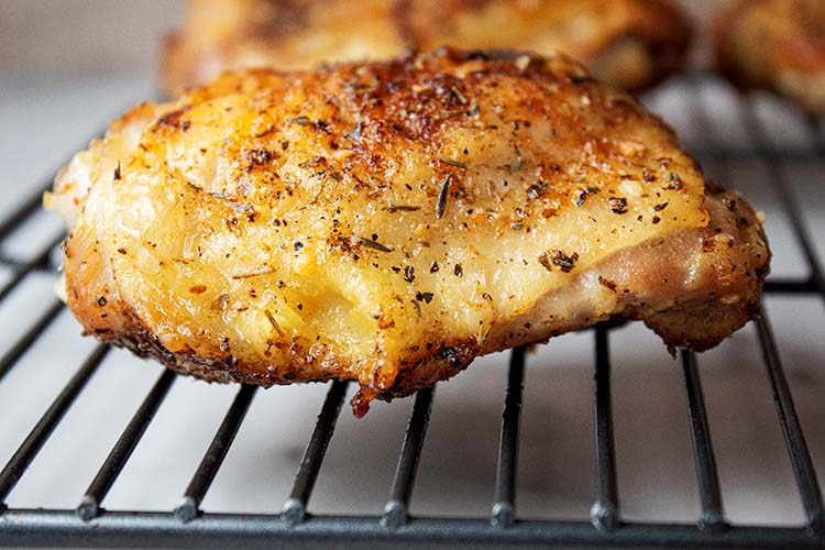 sideview of air fryer garlic parmesan chicken thighs on a cooling rack