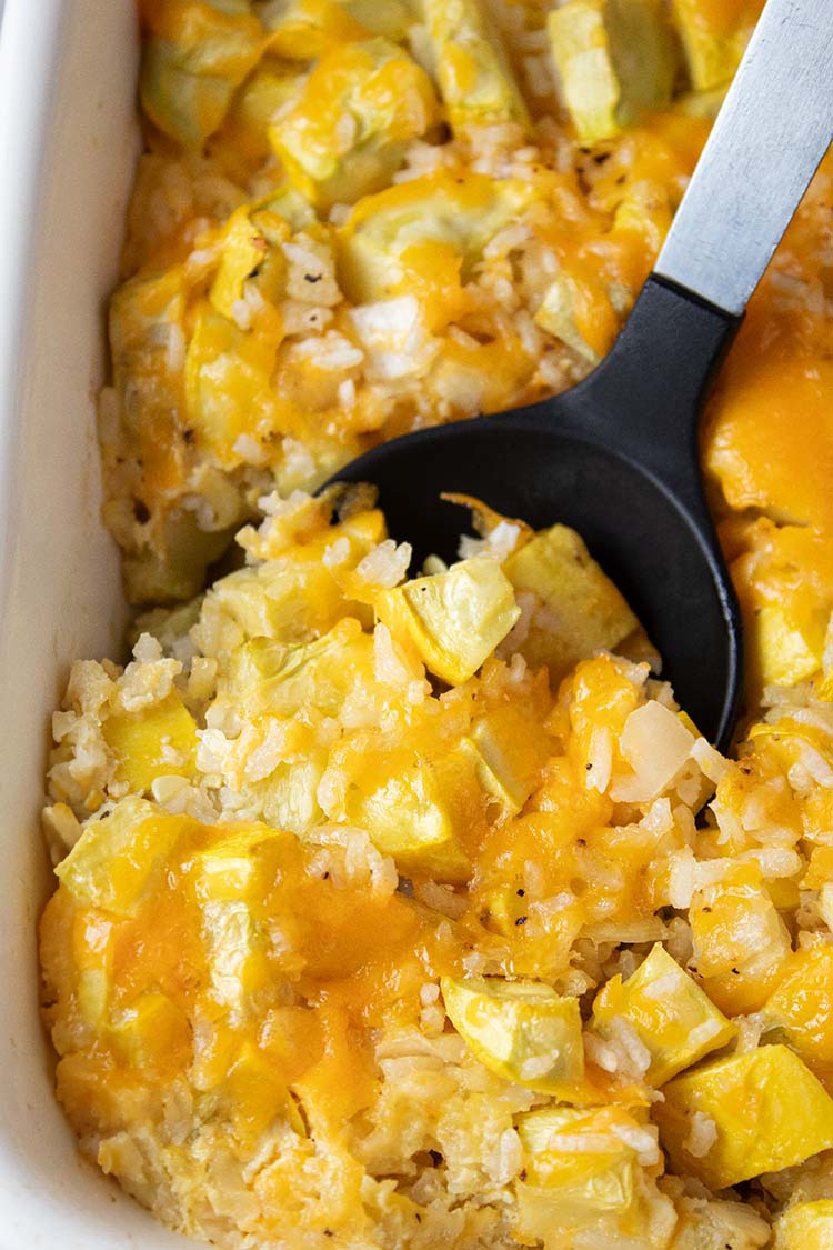 overhead view of summer yellow squash casserole with serving spoon getting scoop of it to put it into a serving dish