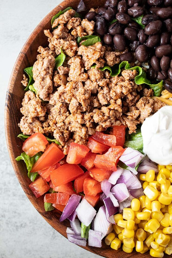overhead view of bowl with turkey taco salad ingredients spaced around and not mixed