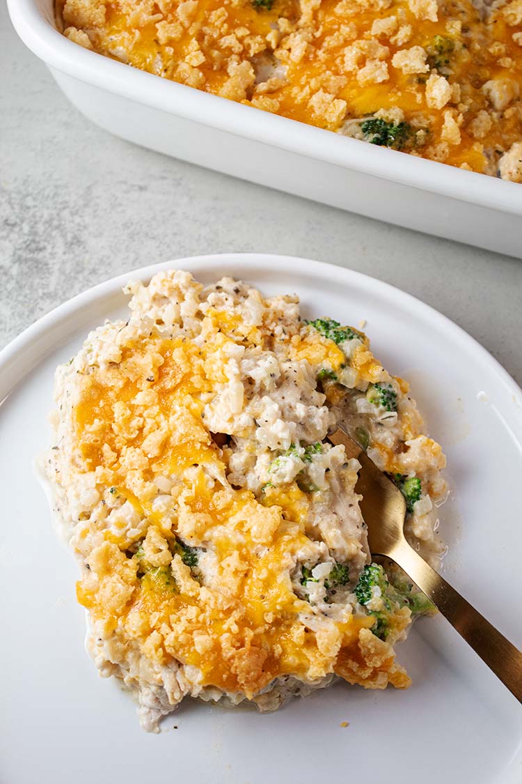 overhead view of chicken cauliflower rice casserole serving on a white plate with a gold serving fork