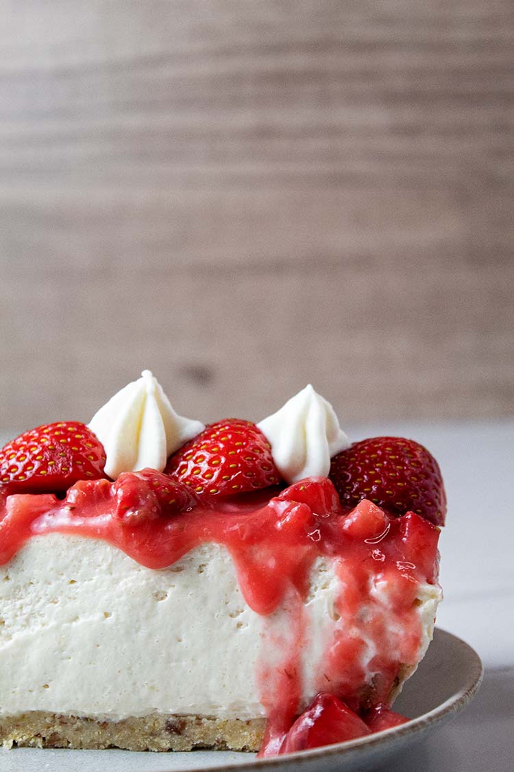 sideview of slice of rhubarb strawberry no bake cheesecake on a serving dish