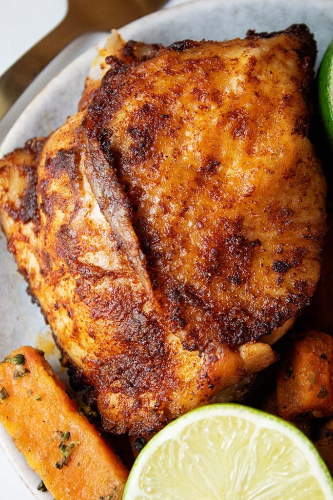 overhead view of air fryer chili and lime chicken on a white serving dish with a lime halve