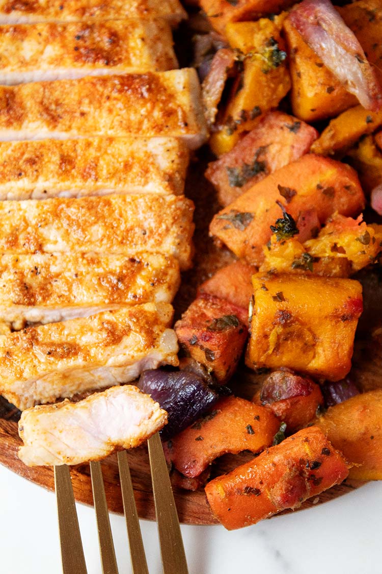 overhead view of ready to serve air fryer pork chops with a side of sweet potatoes and serving fork
