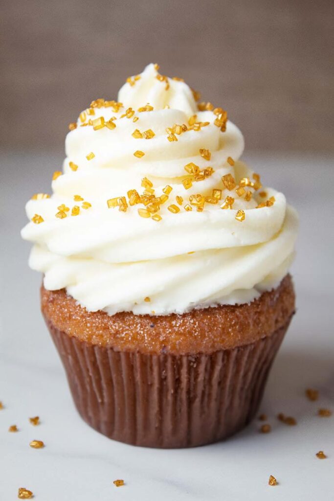 image of cream cheese frosting swirled on a cupcake and topped with sprinkles