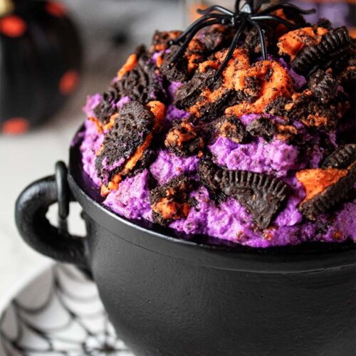 sideview of halloween oreo cheesecake fluff topped with crushed oreos in a black cauldron ready to be served