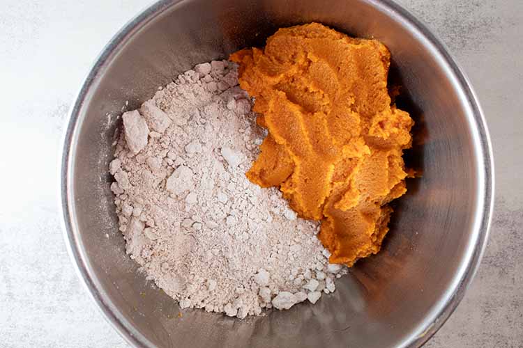 overhead view of pumpkin pie filling and spice cake mix in a silver mixing bowl