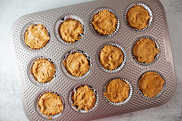 overhead view of pumpkin mix spooned into cupcake wrappers in a cupcake pan
