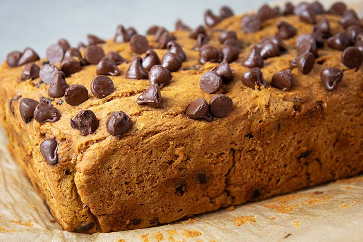 sideview of baked pumpkin bread with chocolate chips out of the oven and ready to be sliced