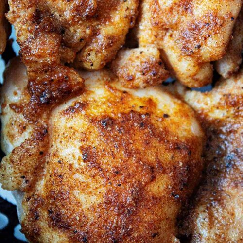 overhead view of air fryer boneless skinless chicken thighs in basket ready to be served