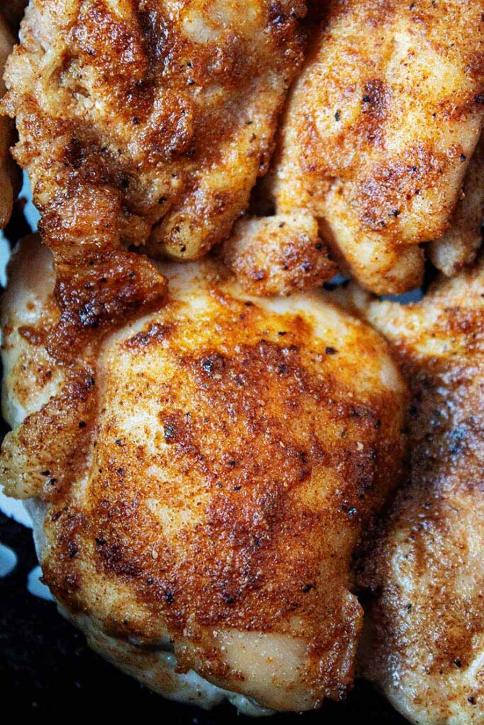 overhead view of air fryer boneless skinless chicken thighs in basket ready to be served