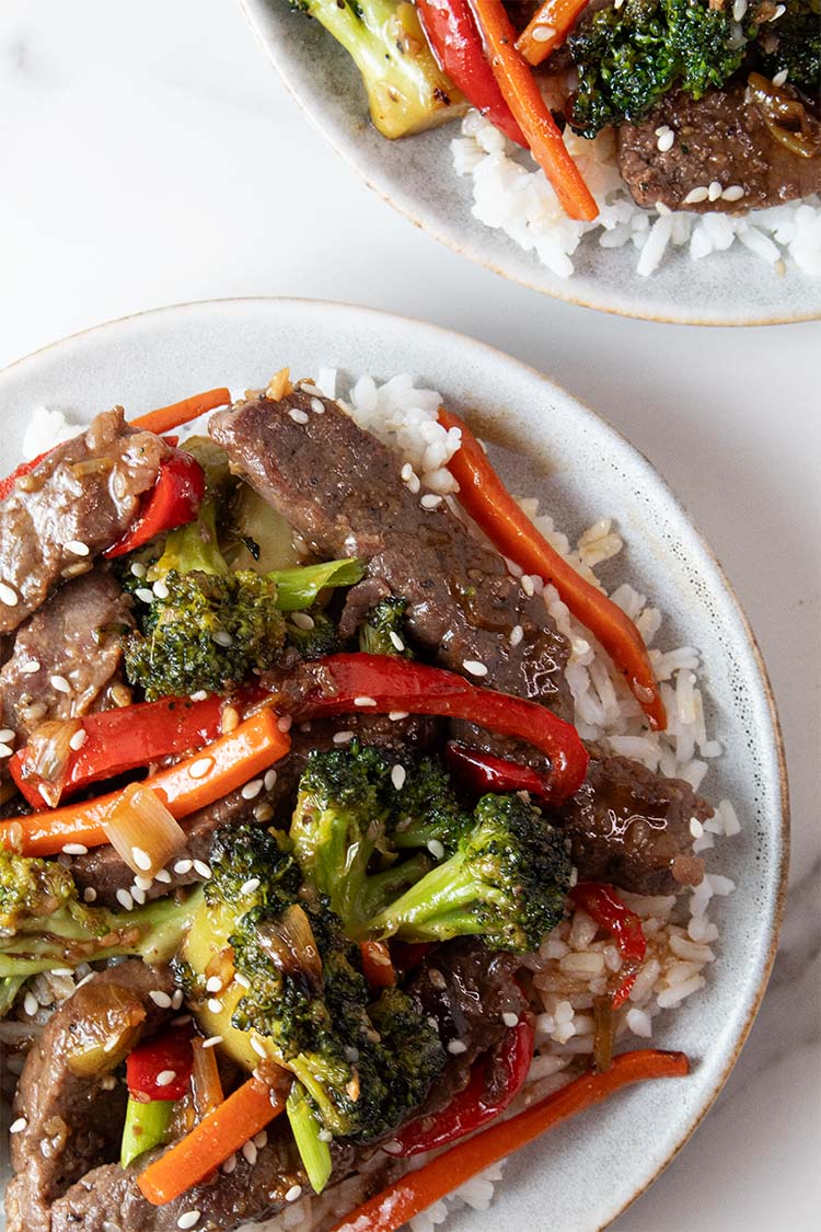 overhead view of freshly made ready to serve broccoli steak stir fry on a white serving dish with white rice