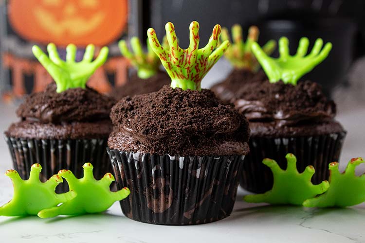sideview of Halloween zombie dirt cupcakes with zombie hand decor sticking out of each one