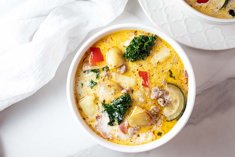 overhead view of ready to serve zuppa toscana soup in a white bowl