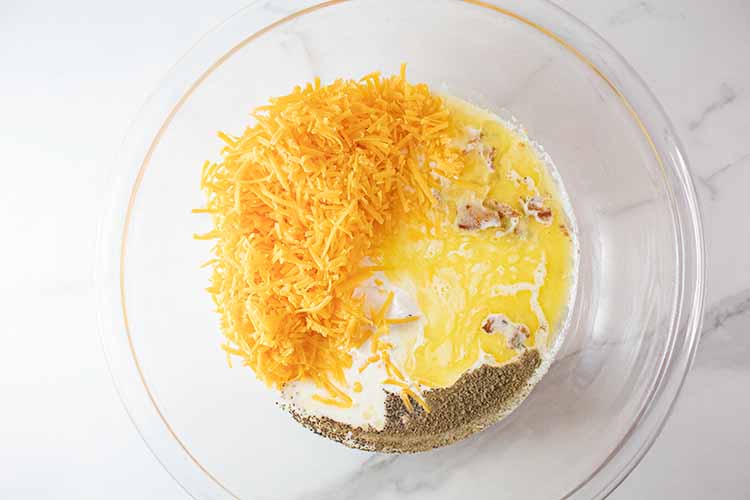 overhead view of ingredients for cheesy mixture in glass mixing bowl ready to be combined