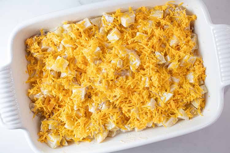overhead view of potato mixture topped with cheese in casserole dish ready to be placed into oven