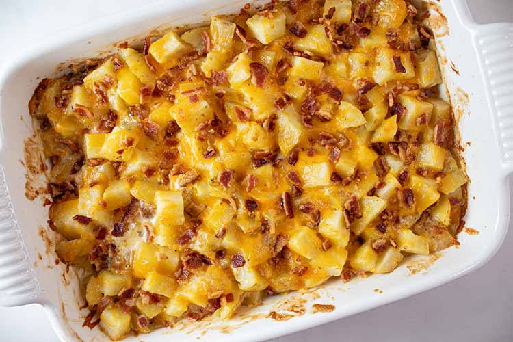 overhead view of cheesy potato casserole out of the oven and cooling off in white casserole dish