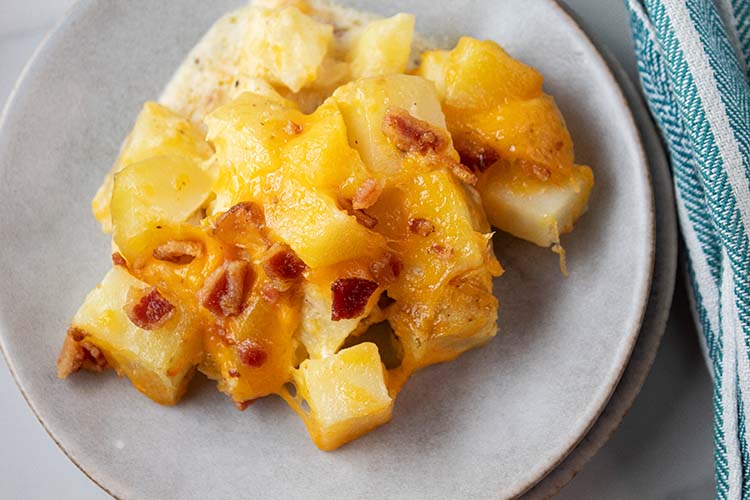 overhead view of portion size of cheesy potato casserole served on a white dish