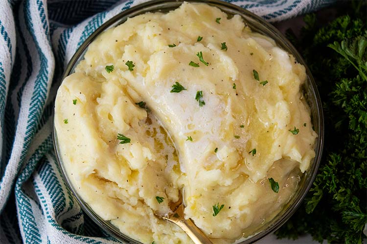 overhead view of ready to serve mashed potatoes in a bowl with a gold spoon