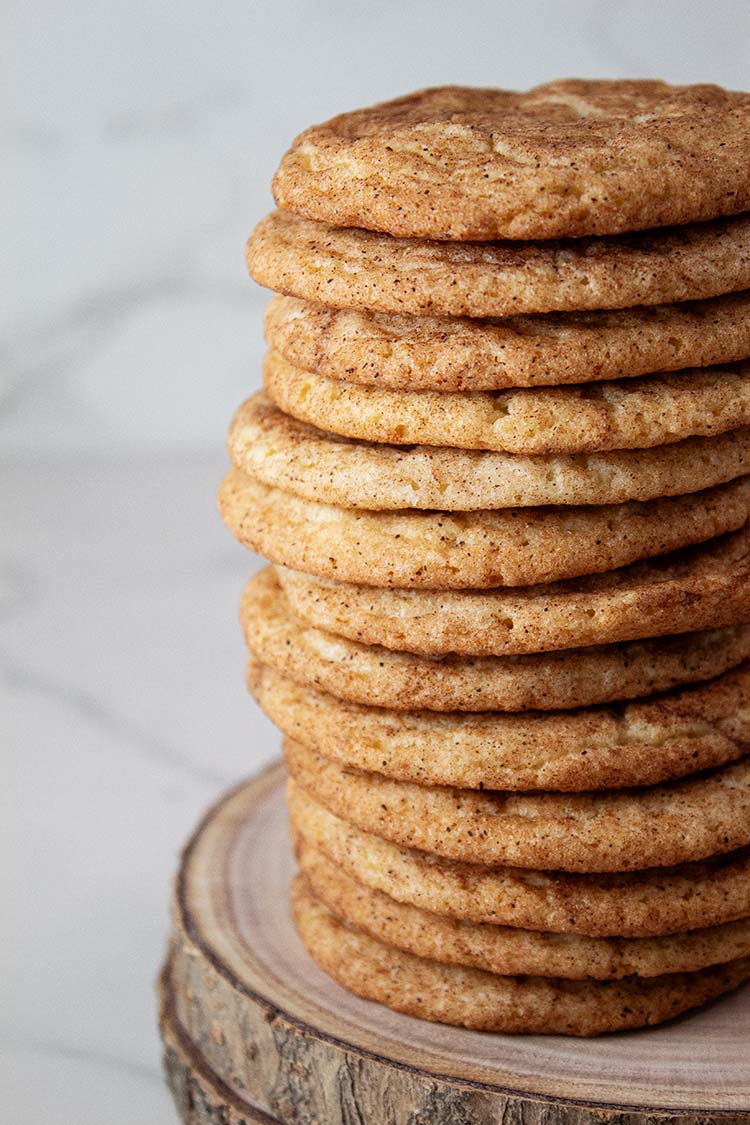 sideview of a stack of 13 snickerdoodle cookies served on a wooden cookie platter