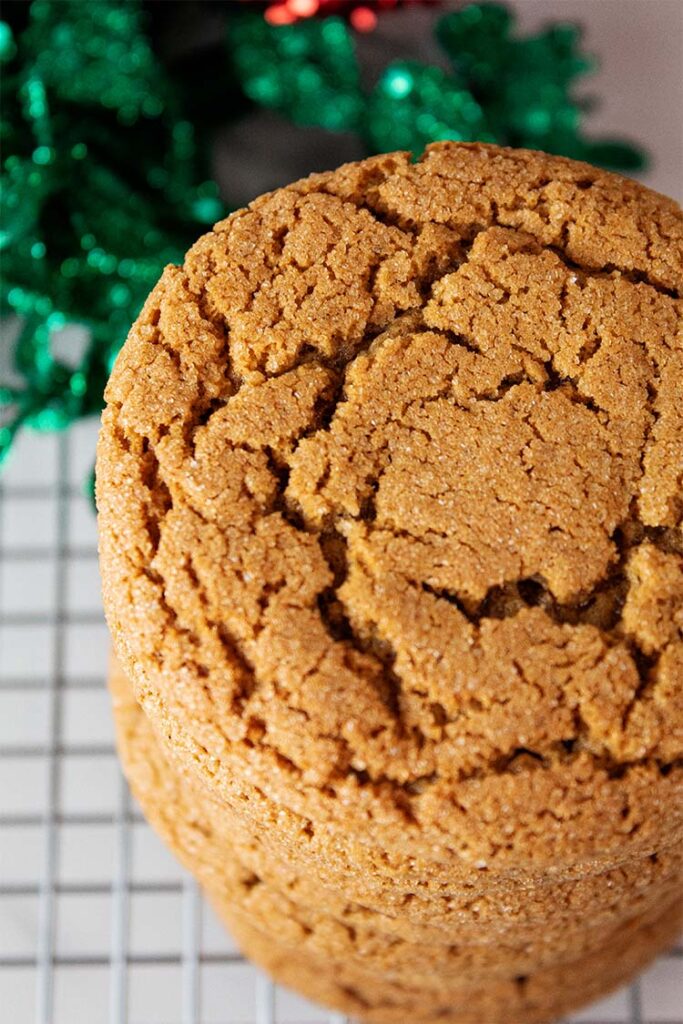 overhead view of a stack of gingerbread cookies on a wire rack with christmas decor in the background