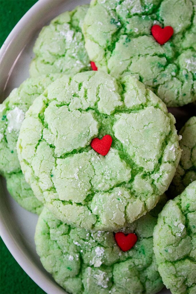 overhead view of grinch cake mix cookies with small candy decorative heart at the center ready to serve on a cookie serving plate