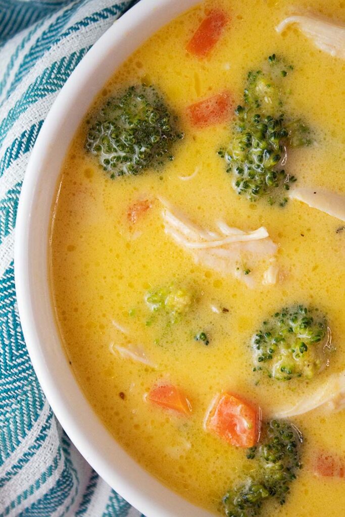 overhead view of broccoli and cheese soup with chicken in a white serving bowl that is ready to serve