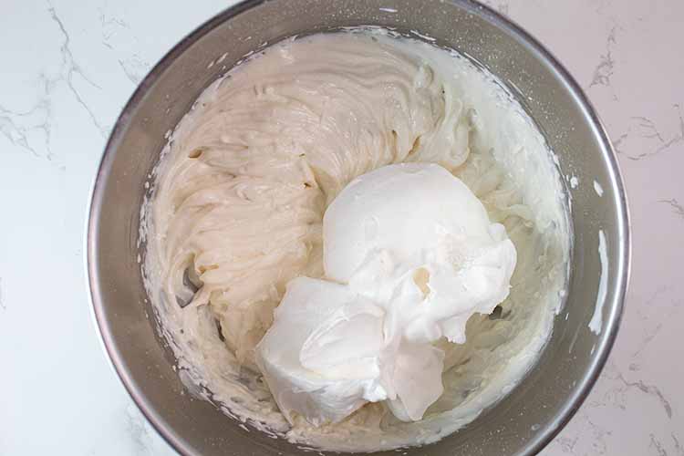 overhead view of whipped cream added to yogurt mixture ready to be mixed