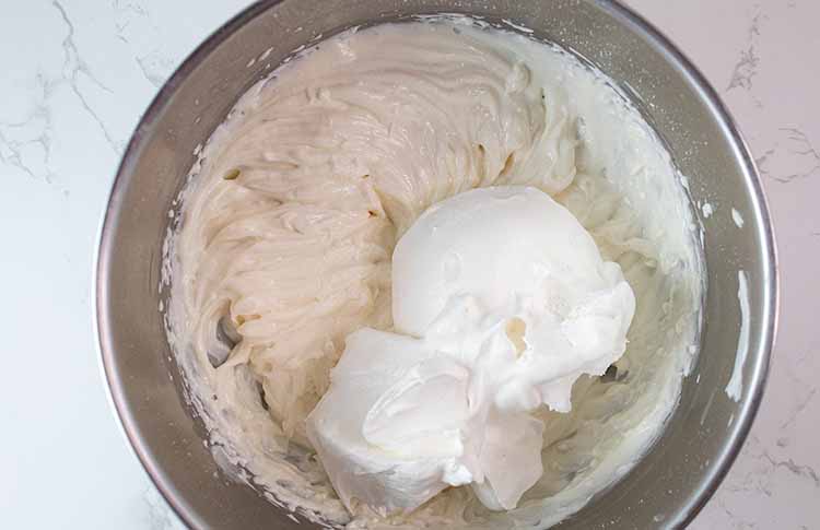 overhead view of whipped cream ready to be combined with yogurt mixture in a mixing bowl