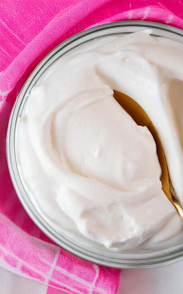 overhead view of high protein cheesecake fluff in a serving bowl and gold serving spoon in it