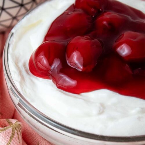 sideview of high protein cherry cheesecake fluff topped with cherries in a serving bowl