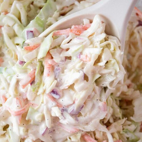 overhead view of coleslaw ready to serve with a large serving spoon removing one serving